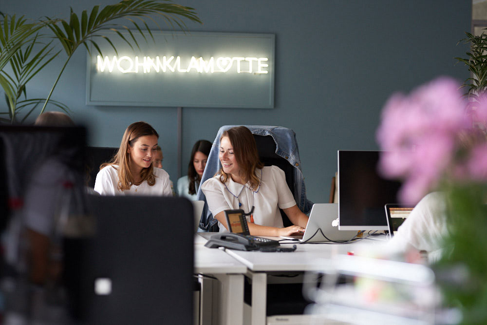 Female employees of shopping24 are sitting at their desks and working together on a project
