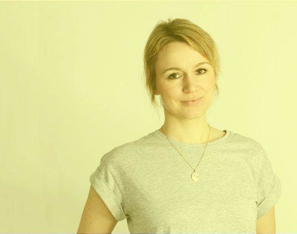 Young woman in t-shirt and arms propped on hips smiles at camera