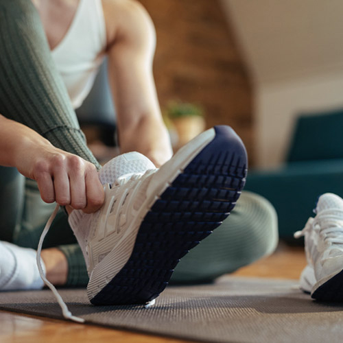 Frau mit Sportbekleidung schnürt sich den Laufschuh.